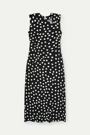Woman wearing a black sleeveless midi dress with white polka dots and a wrap-style bodice, front