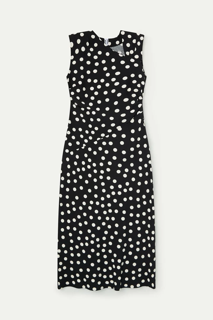 Woman wearing a black sleeveless midi dress with white polka dots and a wrap-style bodice, front