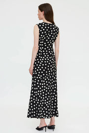 Woman wearing a black sleeveless midi dress with white polka dots and a wrap-style bodice, back
