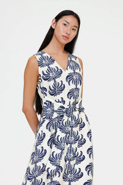 Woman wearing a sleeveless V-neck midi dress with a blue palm print and a tie waist