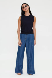 Woman wearing a navy sleeveless knit top with a crew neckline, front view
