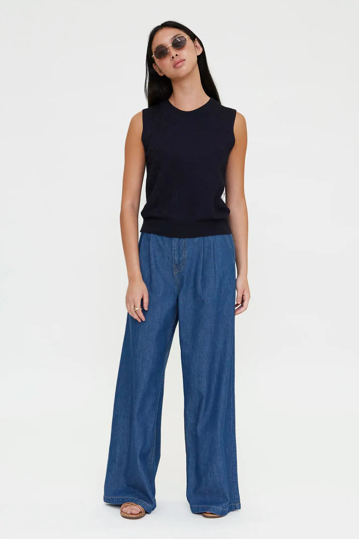 Woman wearing a navy sleeveless knit top with a crew neckline, front view
